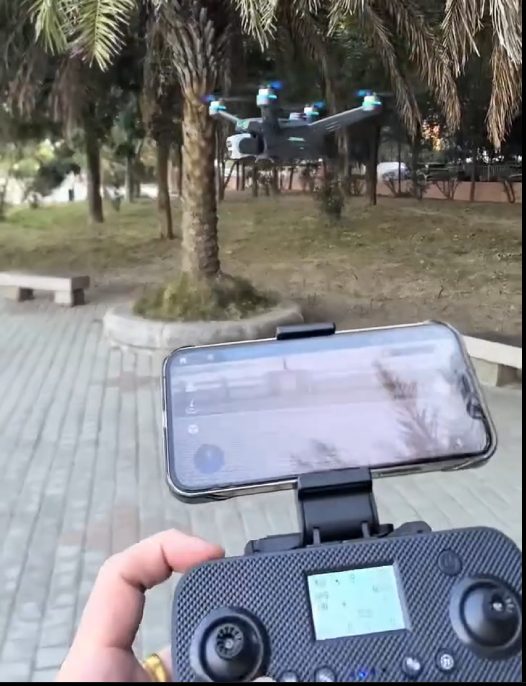 GPS drone hovering outdoors with live view on the screen remote during a return-to-home test